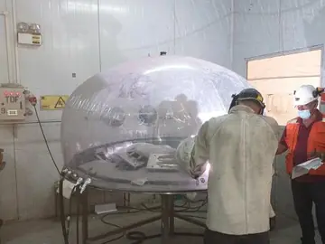 Soldador trabajando en titanio dentro de la cámara de protección